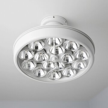 Circular white ceiling light fixture with multiple recessed spotlights mounted on a plain surface