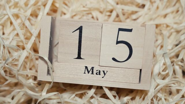 Wooden calendar blocks showing date May 15 on natural wood shavings background