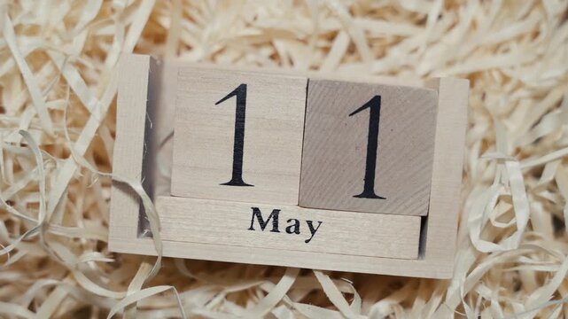 Wooden calendar blocks showing date May 11 on natural wood shavings background
