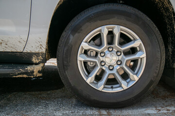 Close-up of a modern silver alloy wheel and Michelin tyre fitted to a white truck covered in fresh brown mud splatters. The detailed tyre sidewall and wheel show evidence of recent off-road trip © Val
