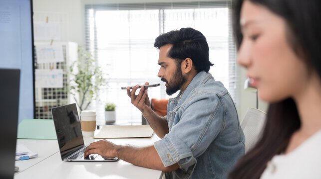 Businessman using AI voice assistant on smartphone in modern high-tech office.