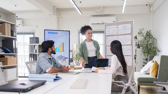Female leader presenting data analysis and project strategy to team in boardroom.