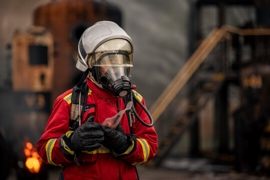 Firefighter Using a Walkie Talkie to Coordinate with the Rescue Team while Wearing a Full Face Mask and Red Protective Uniform