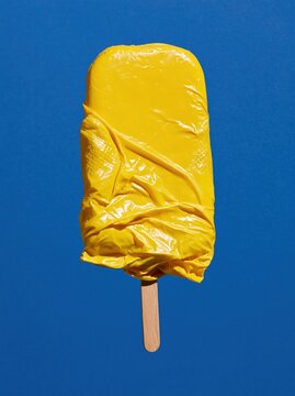 Yellow Rubber Glove Ice Pop with Smooth Central Panel on Cobalt Blue Background