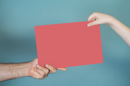 Hand holding blank sign. Hand with red paper. Hand supports poster board. Hands fathers and child together.