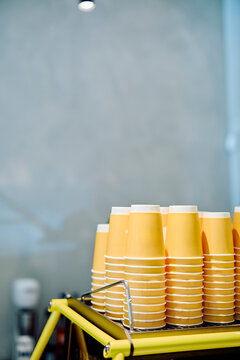 Many yellow disposable paper cups stacked upside down, ready for coffee service at a modern cafe