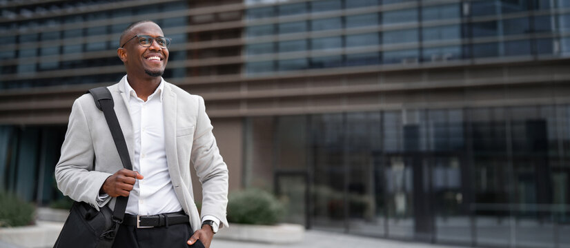 African american businessman, posing for confident portrait, works as executive director, outdoor near office building. Black business man smiling, focused on daily tasks. Copy space. Web banner.