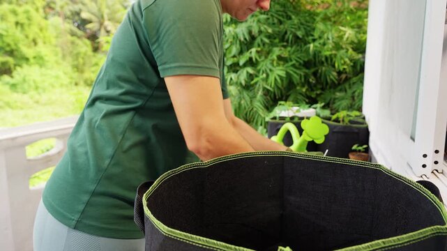 Gardener Pours Soil into a Fabric Grow Bag on an Outdoor Porch, Preparing a Container Planter for Home Gardening and Sustainable Living