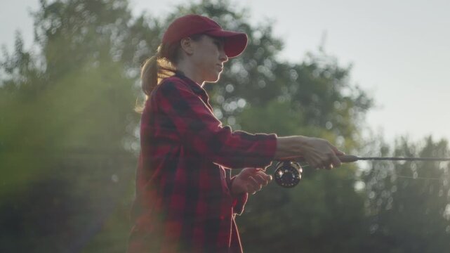 Young woman fly fishing on the small shallow river during summer day