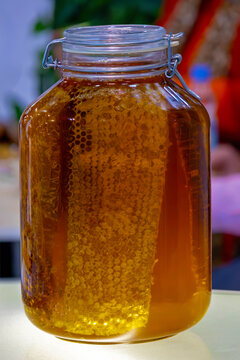 Gold liquid sweet honey with honeycomb inside closed glass jar outside on market