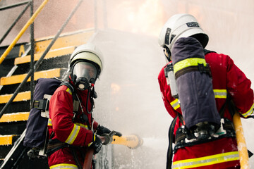 Fototapeta premium Two firefighters spraying water into industrial building during emergency response