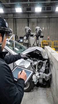 自動車の安全試験施設にて、バリア衝突試験で衝突・変形した車両の構造を分析する日本人自動車安全エンジニア