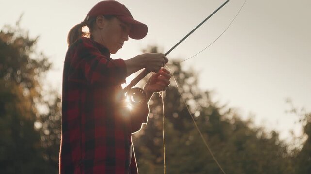 Young woman fly fishing on the small shallow river during summer day
