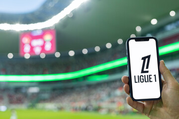 Fototapeta premium MINSK, BELARUS JUNE 9, 2026: Man holding Apple iPhone 12 in the stadium. The official logo of the France national football championship