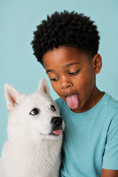 Boy and dog sticking out tongues while sharing a playful look