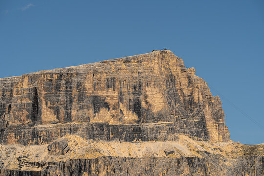 View of the rugged limestone cliffs of Sass Pordoi near Pordoi Pass with dramatic rock faces under a clear blue sky, Canazei, Trentino-Alto Adige, Italy.