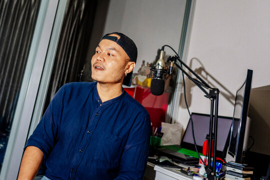Podcast host at home studio sitting near microphone and computer