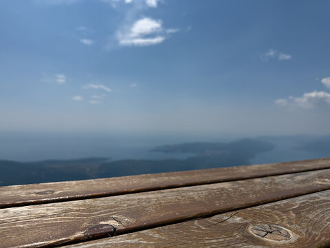 Rustic wooden tabletop overlooking the blue sea and majestic mountains, Mediterranean coastal landscape and summer vacation concept
