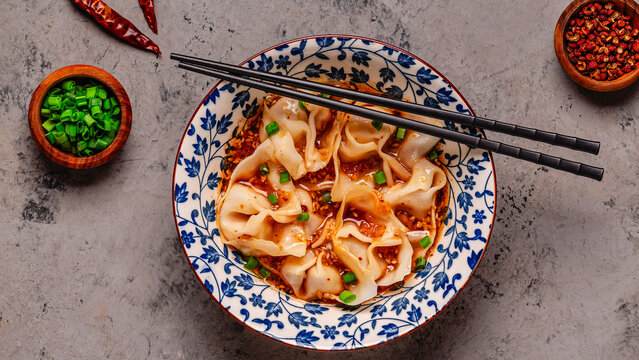 Wontons are placed in a bowl with spicy sauce.