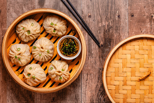 Steam basket with dumplings served with dipping sauce on a wooden table