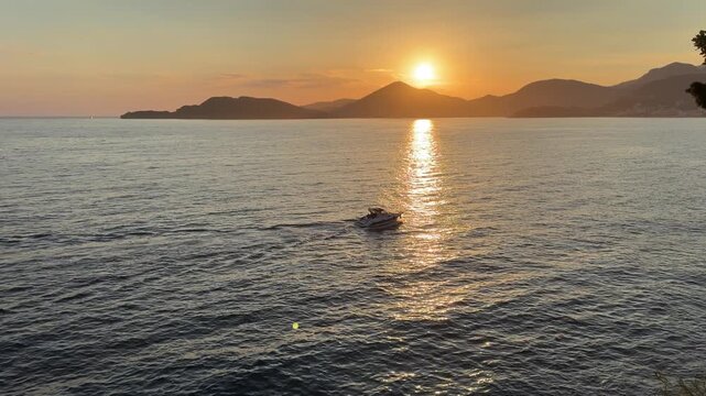 Sailing yacht moving across the sea at sunset, glowing golden light and peaceful maritime landscape