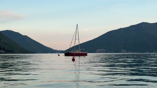 Solitary sailing yacht on the calm sea at sunset, peaceful maritime landscape with warm golden light and serene summer atmosphere