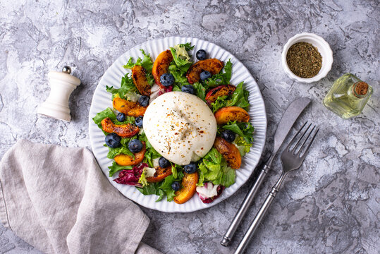 Delicious salad with burrata cheese grilled peaches and blueberry