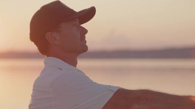 Young man fishing on the river during sunset and casts a lure