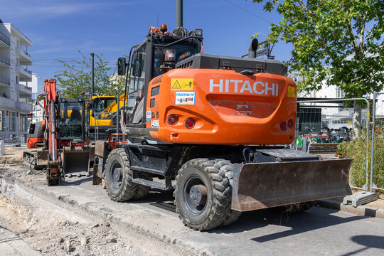 Nancy, France - August 8th 2026 : View on an orange wheeled excavator Hitachi ZX145W on a construction site for work on the district heating network.