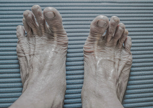 Close up of old woman's feet on blue corrugated background