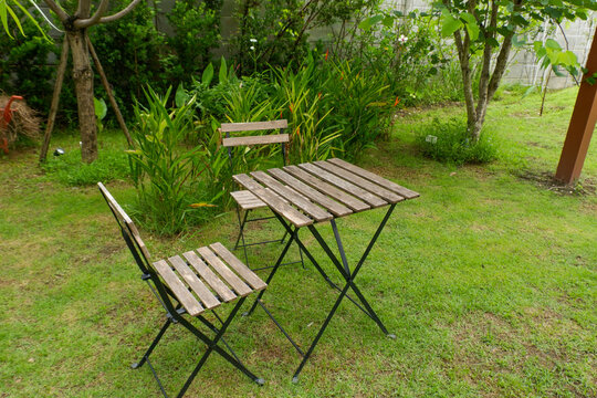 Wooden table and chair set in garden on a sunny day,outdoor seating for restaurant or cafe,Neat paved patio with sitting area and small garden in forest.