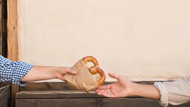 Person handing fresh soft pretzel to customer