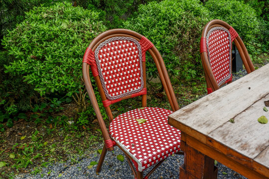 Luxury chair and wooden table set in english garden on a sunny day,outdoor seating for restaurant or cafe,Near paver patio with sitting area and small garden in forest.