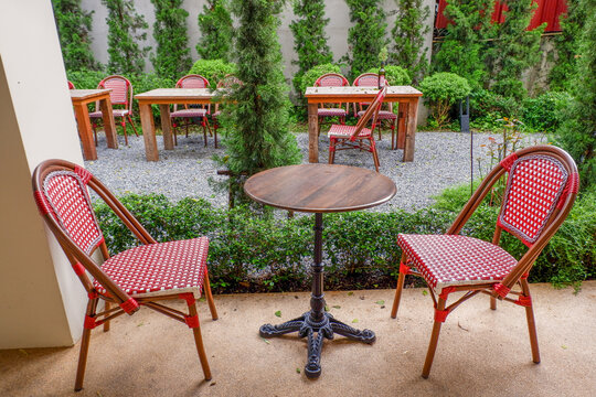 Luxury chair and wooden table set in english garden on a sunny day,outdoor seating for restaurant or cafe,Near paver patio with sitting area and small garden in forest.