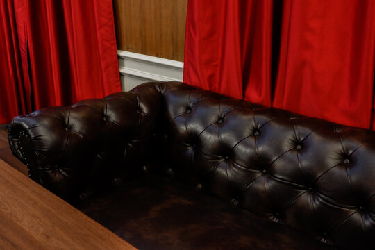 Black soft leather luxurious sofa in living room with curtain red,mock up interior in classic style, modern interior design concept.