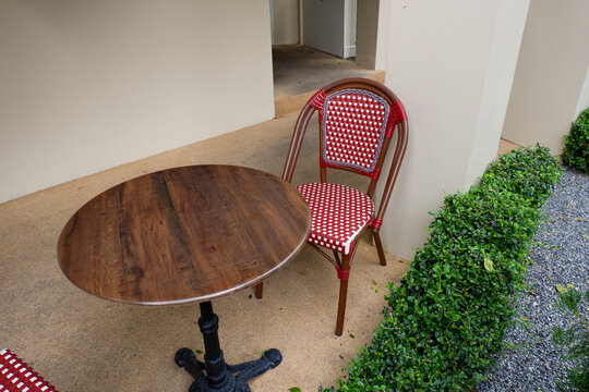 Luxury chair and wooden table set in english garden on a sunny day,outdoor seating for restaurant or cafe,Near paver patio with sitting area and small garden in forest.