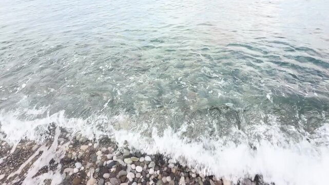 Blue sea and large waves and foam. Wave splashing over pebbles at sea. Rolling ocean waves. Summer beach background. Powerful sea waves	