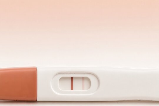 Pregnancy test with positive result on soft pink background