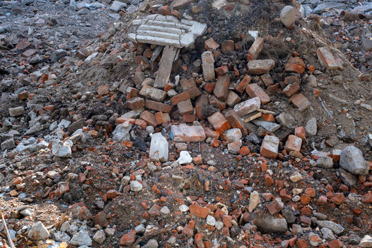 Close-up view of construction and demolition debris consisting of broken red bricks, concrete fragments, stones and wood. Detailed texture of building rubble at an urban demolition site.
