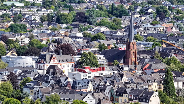 Vogelperspektive auf Trier mit dem markanten Turm der Herz-Jesu-Kirche, umgeben von einer dichten Struktur aus Wohnh&auml;usern, historischen Fassaden und gr&uuml;nen B&auml;umen.