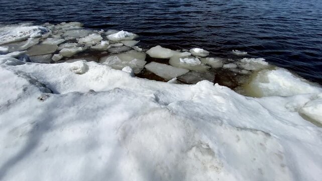 Water flowing from a concrete culvert storm drain pipe into a rocky creek bed during winter snowmelt in a forest.