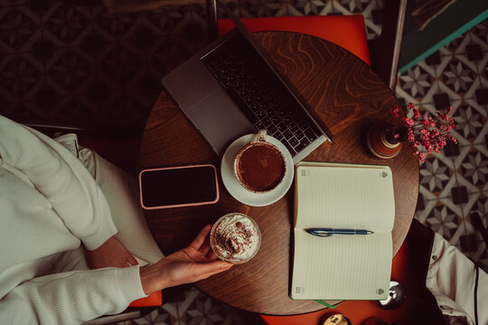 Remote worker using a laptop and phone in a cafe