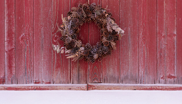 Pinecone Wreath on Weathered Red Barn Door with Snow