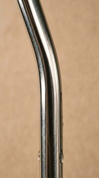 Shiny metallic tube curves gracefully against warm-toned background