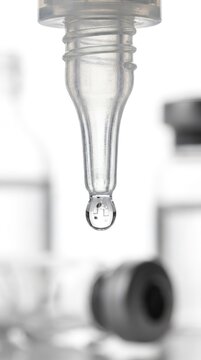 Single drop hangs from glass dropper tip