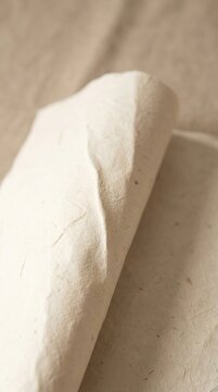 Soft, cream-colored fabric rolls gently on a neutral surface
