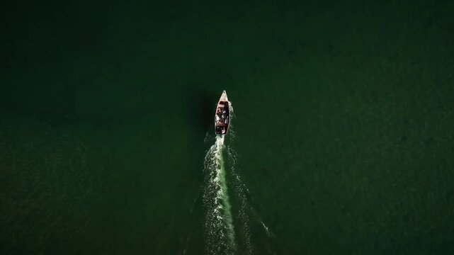 Aerial view of a small boat moving across the dark waters of Boca Chavon, creating a white wake in La Romana, La Romana, Dominican Republic.