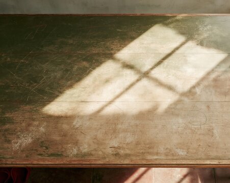 Weathered green wooden table with scratched texture and window light, showing a rustic worn surface for domestic kitchen backdrops and parenting layouts