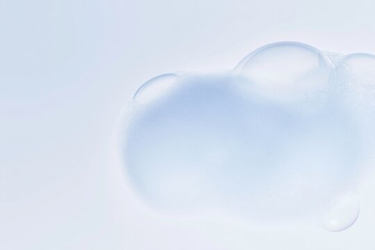 Light blue soap foam sits on a pale surface with visible bubbles and airy texture for cosmetic packaging and skincare product concepts