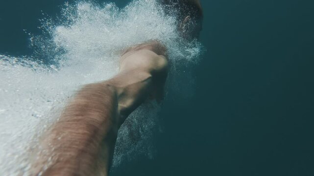 Young man jumps into the sea from a boat and swims underwater